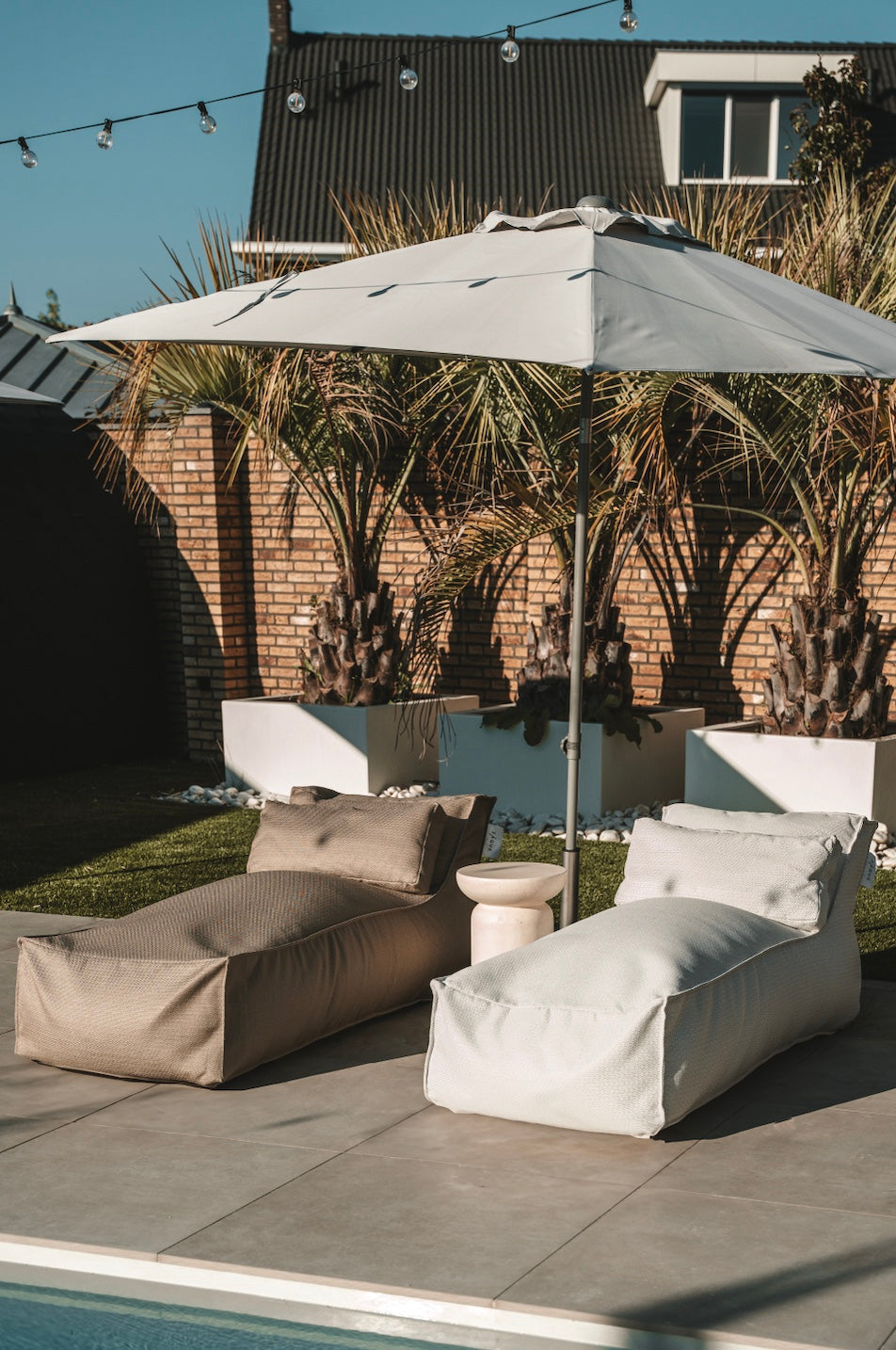 Outdoor patio with lounge chairs, umbrella, and pool area.
